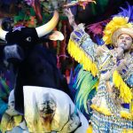 Show do Boi Caprichoso no Bumbódromo, com cantor e boi-bumbá estilizado.