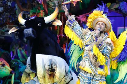 Show do Boi Caprichoso no Bumbódromo, com cantor e boi-bumbá estilizado.