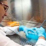 Técnica em laboratório utilizando pipeta em tubos de ensaio.