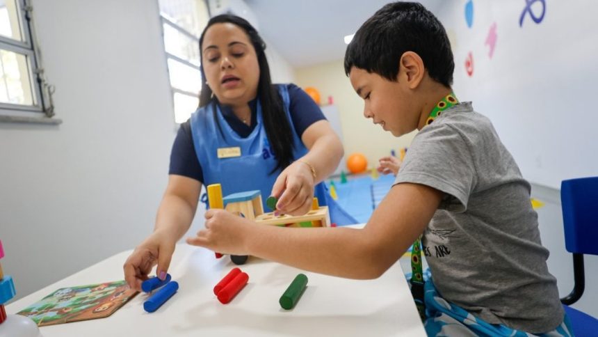 Terapeuta e criança brincando com brinquedos educativos em sala de aula.