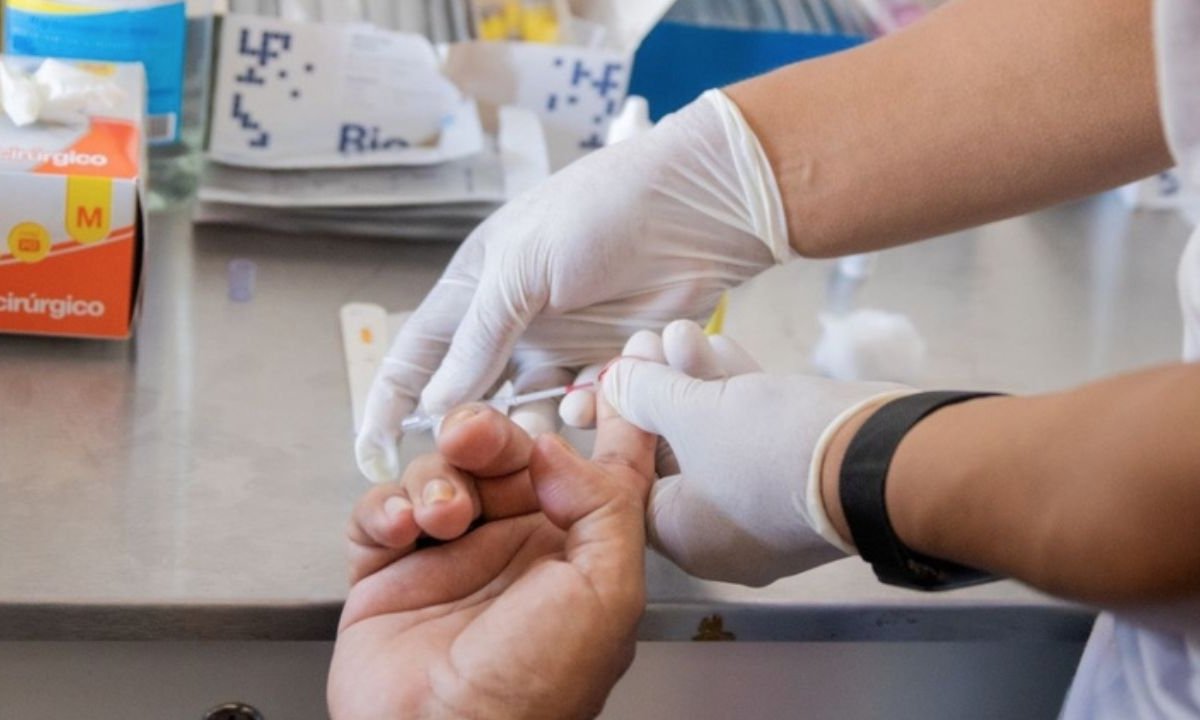 Teste de sangue para sífilis em jovem adulto. Profissional com luvas coleta amostra.