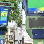 Totem de reconhecimento facial pichado em praça, exibindo mensagens.