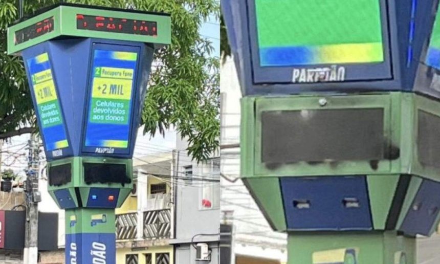 Totem de reconhecimento facial pichado em praça, exibindo mensagens.