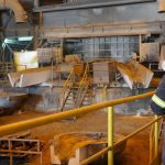 Trabalhador em fábrica de mineração com equipamento de proteção individual (EPI).