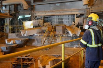 Trabalhador em fábrica de mineração com equipamento de proteção individual (EPI).