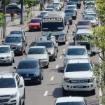 Trânsito intenso em Manaus com vários carros e ônibus na via durante o dia.