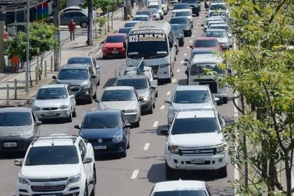 Trânsito intenso em Manaus com vários carros e ônibus na via durante o dia.