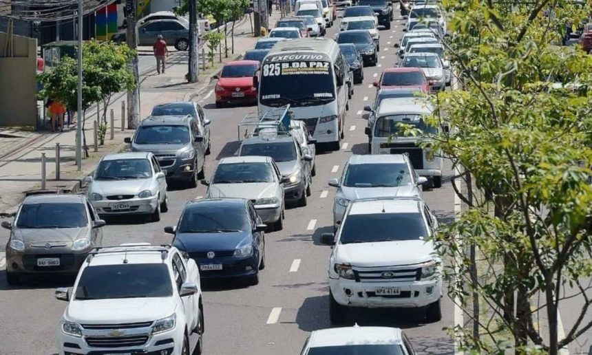Trânsito intenso em Manaus com vários carros e ônibus na via durante o dia.