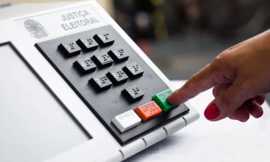 Urna eletrônica com dedo pressionando o botão de confirmação, simbolizando votação.