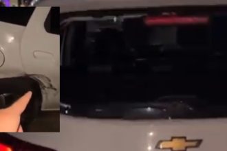 Veículo branco com danos na lataria e pneu, possivelmente após ataque.