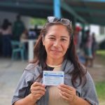 Mulher sorrindo segura o Cartão do Produtor Primário