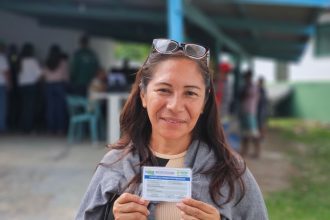 Mulher sorrindo segura o Cartão do Produtor Primário