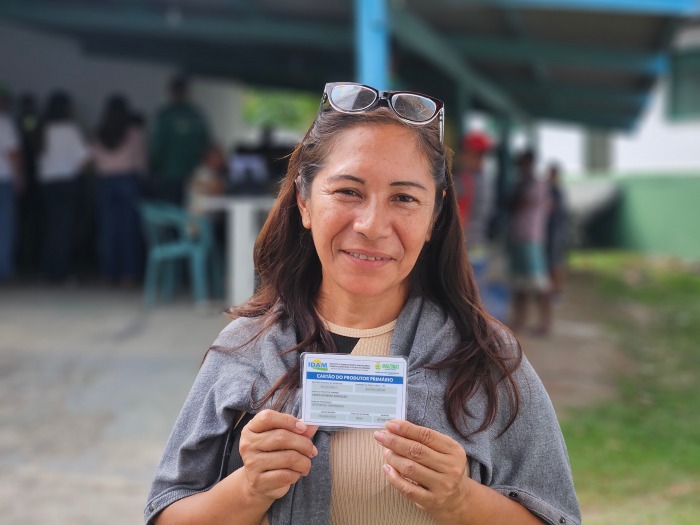 Mulher sorrindo segura o Cartão do Produtor Primário