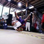 Batalha de breaking em evento de hip hop, com um dançarino em movimento.