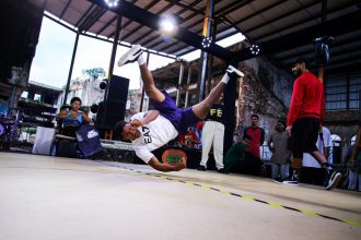 Batalha de breaking em evento de hip hop, com um dançarino em movimento.