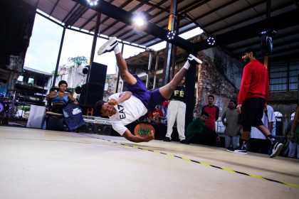 Batalha de breaking em evento de hip hop, com um dançarino em movimento.