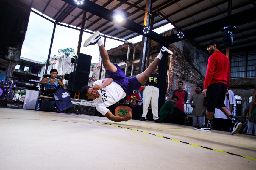 Batalha de breaking em evento de hip hop, com um dançarino em movimento.