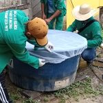 Profissionais inspecionando reservatório de água com rede de proteção, ação de combate a arboviroses no Amazonas.