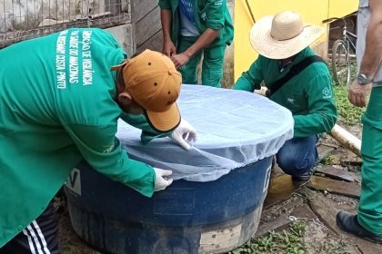 Profissionais inspecionando reservatório de água com rede de proteção, ação de combate a arboviroses no Amazonas.