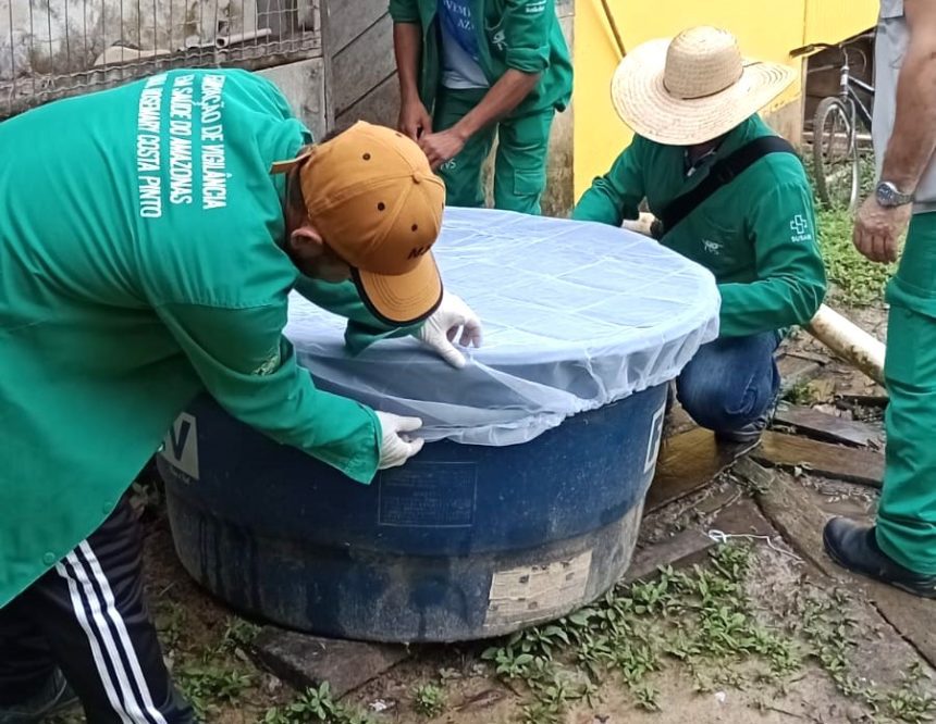 Profissionais inspecionando reservatório de água com rede de proteção, ação de combate a arboviroses no Amazonas.