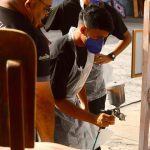 Alunos pintando cadeiras durante oficina de pintura cênica do projeto Ópera nas Escolas em Manaus.