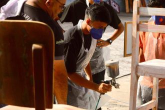 Alunos pintando cadeiras durante oficina de pintura cênica do projeto Ópera nas Escolas em Manaus.
