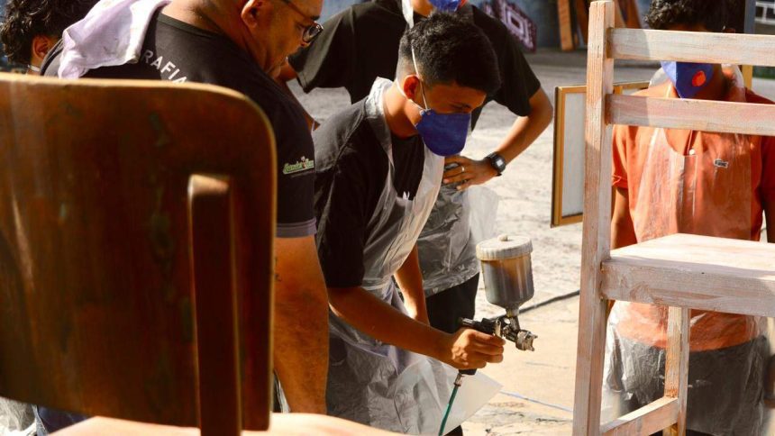 Alunos pintando cadeiras durante oficina de pintura cênica do projeto Ópera nas Escolas em Manaus.