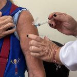 Aplicação de vacina contra a gripe em braço de paciente.