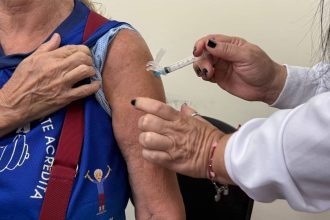 Aplicação de vacina contra a gripe em braço de paciente.