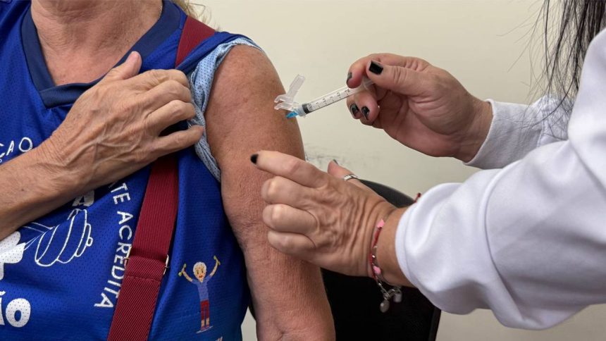 Aplicação de vacina contra a gripe em braço de paciente.