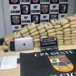 Apreensão de drogas pela polícia, com blocos embalados e materiais de investigação.