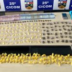 Apreensão de drogas pela Polícia Militar: sacolas com substâncias ilícitas e dinheiro sobre a mesa.