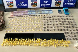 Apreensão de drogas pela Polícia Militar: sacolas com substâncias ilícitas e dinheiro sobre a mesa.