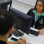 Atendente do Sine Manaus auxiliando cliente em frente a computador.