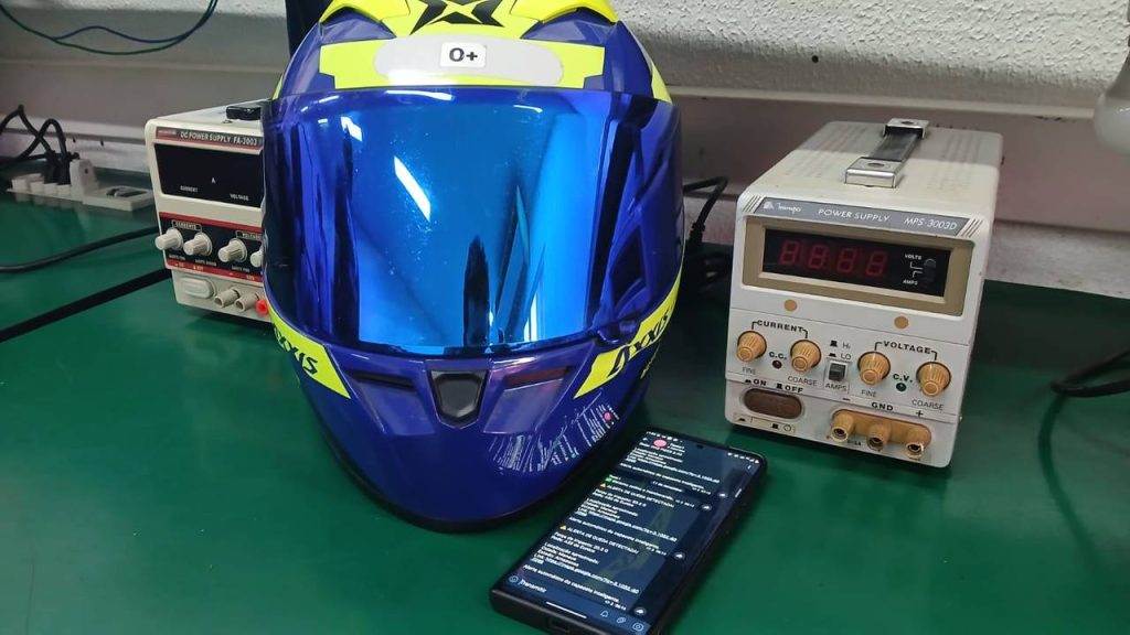 Protótipo de capacete inteliente, equipamentos eletrônicos e celular na mesa.