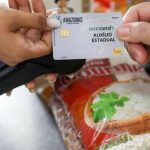 Cartão AvanCard Auxílio Estadual sendo usado em supermercado, com destaque para a embalagem de arroz Gourmet.