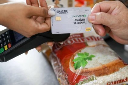 Cartão AvanCard Auxílio Estadual sendo usado em supermercado, com destaque para a embalagem de arroz Gourmet.