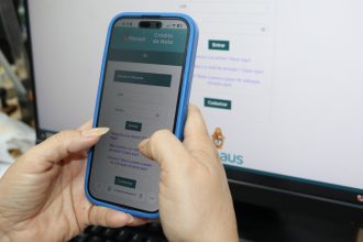 Celular com aplicativo 'Crédito da Nota' de Manaus e tela de login.
