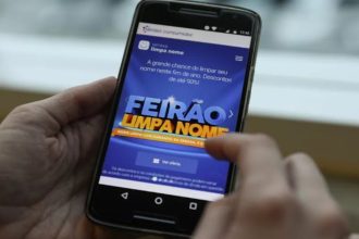Celular mostrando a tela do Feirão Limpa Nome da Serasa, com descontos de até 90%.