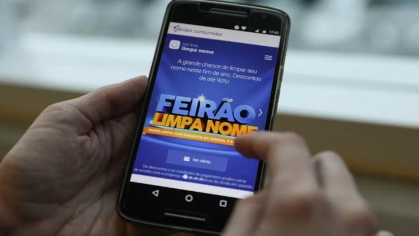 Celular mostrando a tela do Feirão Limpa Nome da Serasa, com descontos de até 90%.