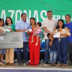 Cerimônia de entrega do Auxílio Estadual a novos beneficiários no Amazonas, com cartão e cheques.