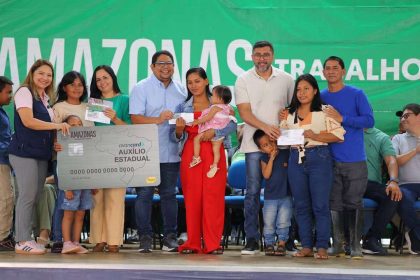 Cerimônia de entrega do Auxílio Estadual a novos beneficiários no Amazonas, com cartão e cheques.