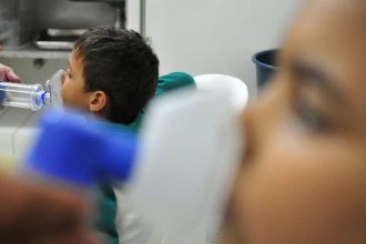 Criança recebe tratamento respiratório com máscara de inalação, em ambiente hospitalar.