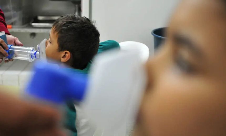 Criança recebe tratamento respiratório com máscara de inalação, em ambiente hospitalar.