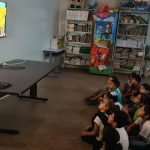 Crianças assistem a filme "Cine Mitos da Amazônia" em sala de aula.