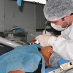 Dentista da UFAM realizando procedimento odontológico em paciente.