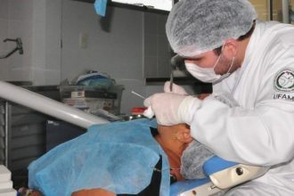 Dentista da UFAM realizando procedimento odontológico em paciente.