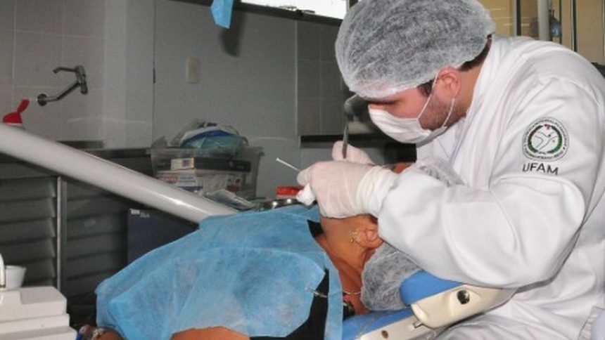 Dentista da UFAM realizando procedimento odontológico em paciente.