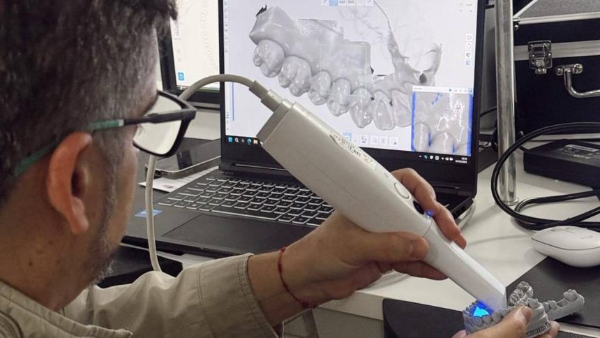 Dentista usando scanner intraoral para digitalizar um molde dentário e analisar em um computador.
