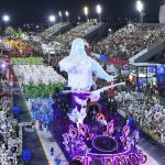 Desfile de escola de samba em Manaus com alegoria e público nas arquibancadas.